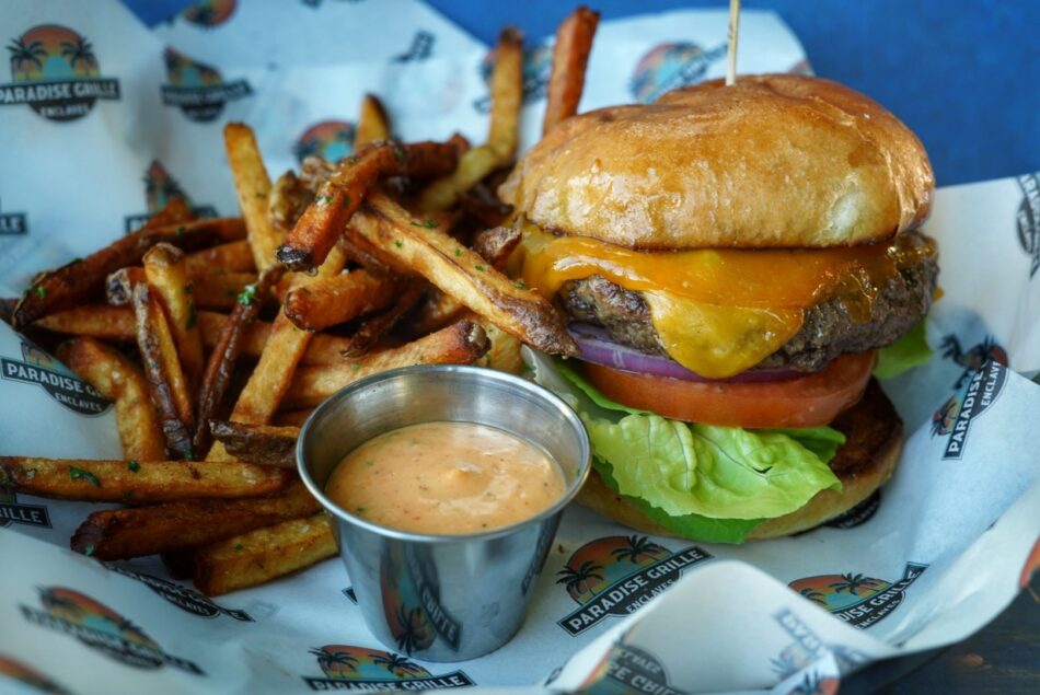 Paradise Burger with hand-cut fries in a basket on branded paper